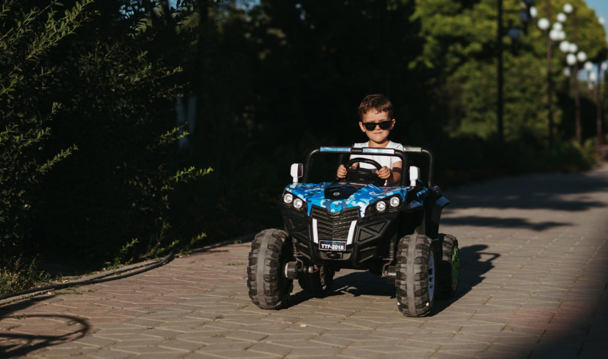petit garçon sur un buggy électrique roulant au soleil avec des lunettes de soleil