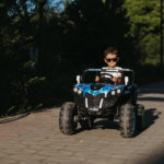 petit garçon sur un buggy électrique roulant au soleil avec des lunettes de soleil