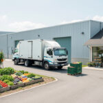 Illustration réaliste et lumineuse d’une chaîne logistique alimentaire reliant une ferme, un camion électrique, un entrepôt frigorifique et un magasin de quartier.